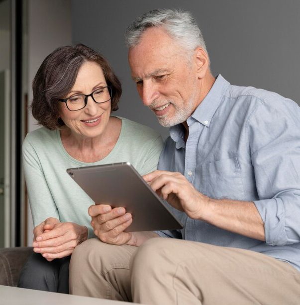 Medium shot smiley seniors with tablet people-looking-picture-album-scaled-img